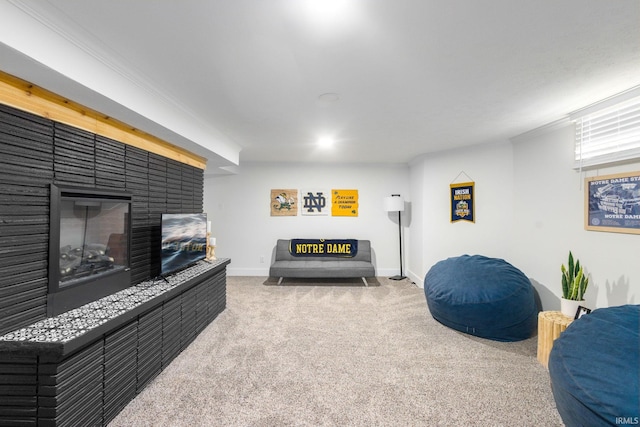 carpeted living area with baseboards, crown molding, and a glass covered fireplace