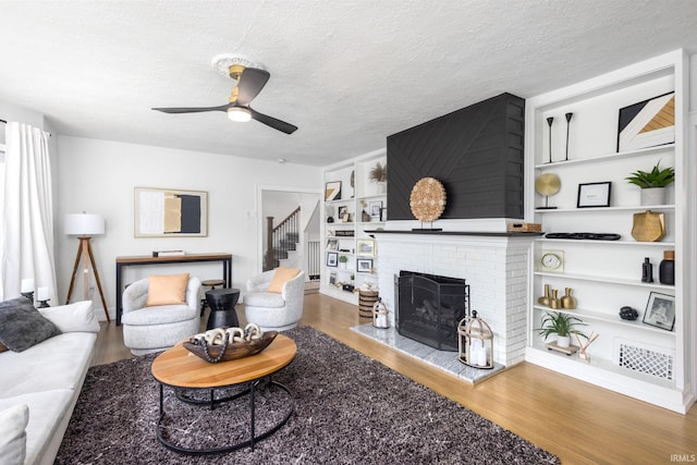 living room with a fireplace, wood finished floors, and a ceiling fan