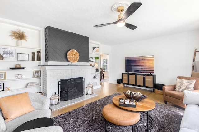 living area with wood finished floors, a ceiling fan, and a fireplace