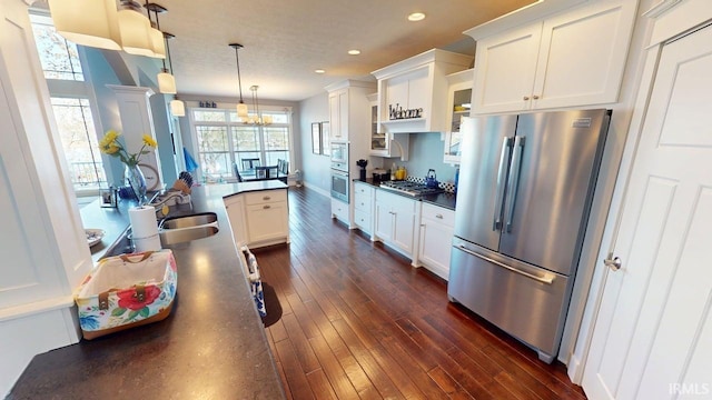 kitchen featuring recessed lighting, a sink, stainless steel appliances, white cabinetry, and dark countertops