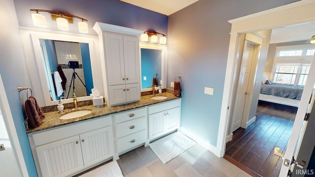 ensuite bathroom with baseboards, ensuite bath, double vanity, and a sink