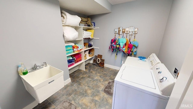 washroom with baseboards, stone finish floor, laundry area, and independent washer and dryer