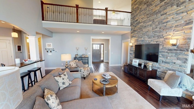 living area featuring dark wood-style floors, baseboards, and arched walkways