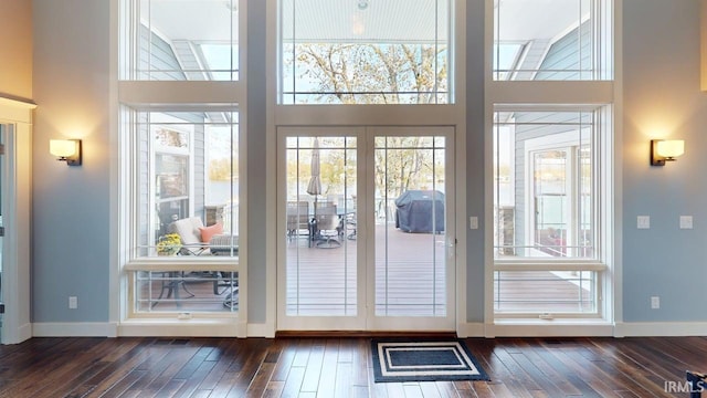 doorway featuring baseboards, a high ceiling, and dark wood-type flooring