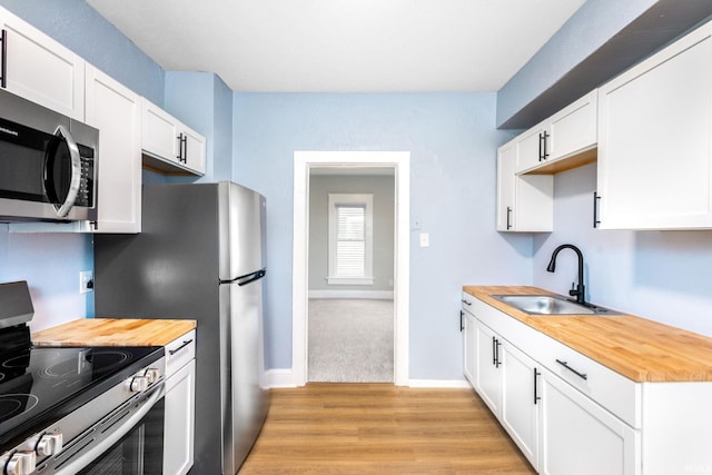kitchen featuring light wood-type flooring, stainless steel appliances, butcher block countertops, and a sink
