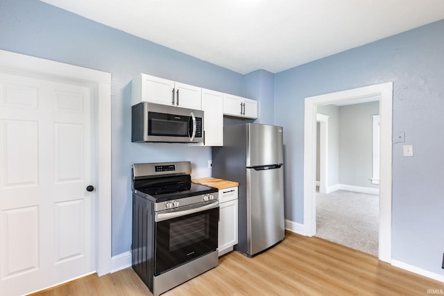 kitchen with white cabinetry, baseboards, stainless steel appliances, and light wood-style flooring