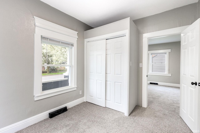 unfurnished bedroom featuring a closet, visible vents, and light carpet