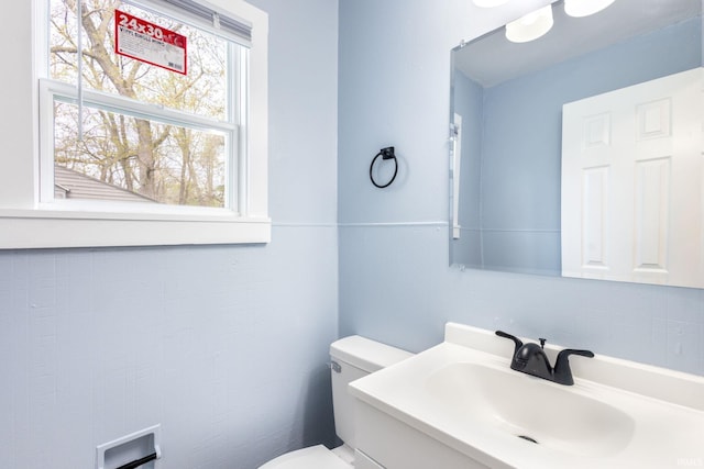 bathroom featuring tasteful backsplash, toilet, and a sink
