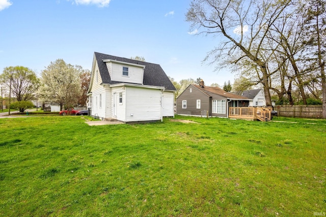 back of property featuring fence, a yard, and a wooden deck
