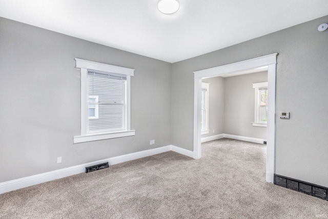 carpeted spare room featuring visible vents and baseboards