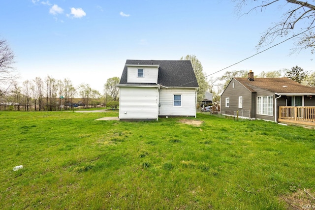 rear view of property with a yard and a shingled roof