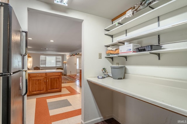 interior space featuring light floors, freestanding refrigerator, brown cabinetry, open shelves, and light countertops