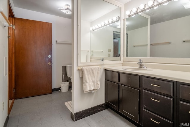 bathroom featuring toilet, vanity, and baseboards