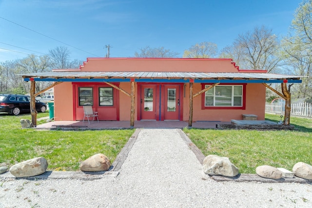 view of front of property with fence, stucco siding, a front yard, and metal roof