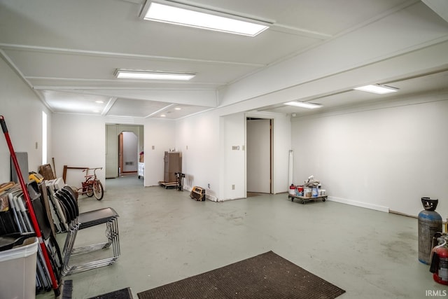 basement with baseboards, recessed lighting, and arched walkways