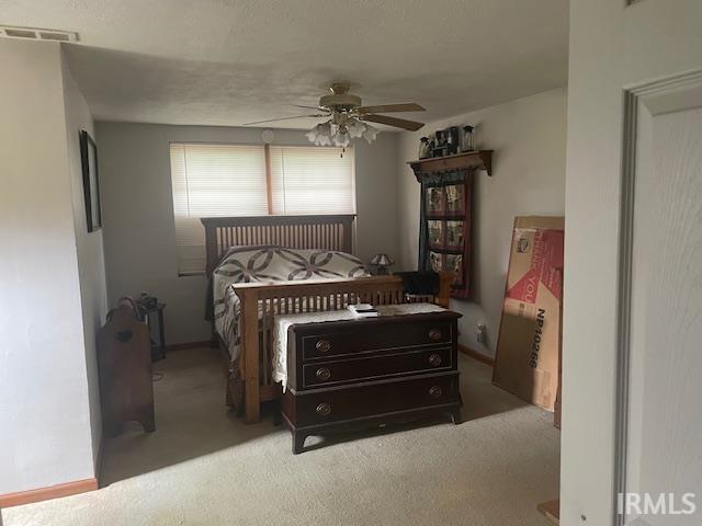 carpeted bedroom with visible vents and a ceiling fan