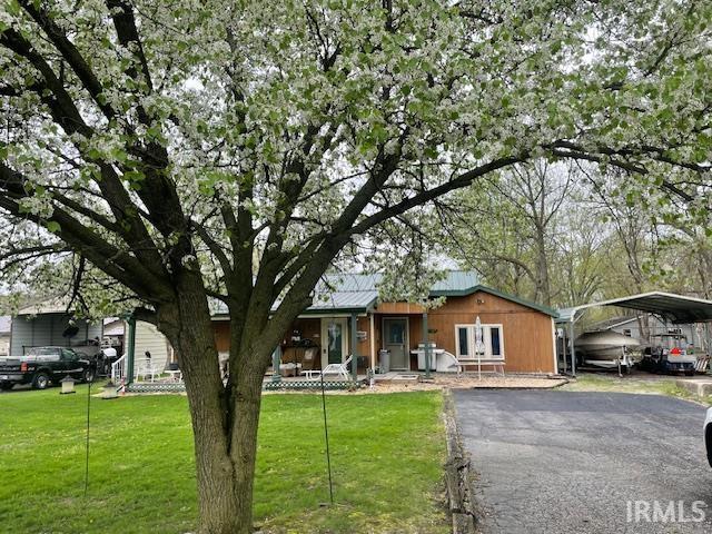 view of front of house with a porch, a front lawn, a carport, and driveway