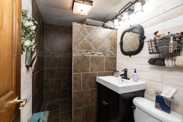 bathroom featuring toilet, tiled shower, and vanity