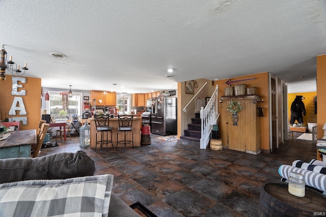 living area featuring visible vents, stone finish floor, stairs, and a textured ceiling
