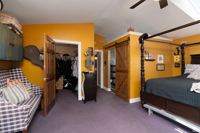carpeted bedroom with a barn door, a closet, a ceiling fan, a walk in closet, and lofted ceiling