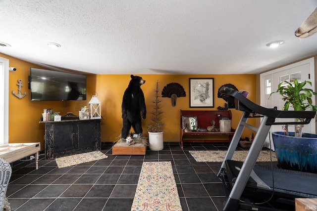 workout area featuring tile patterned floors, visible vents, and a textured ceiling