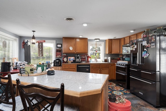 kitchen with a sink, brown cabinets, tile counters, black appliances, and a breakfast bar area