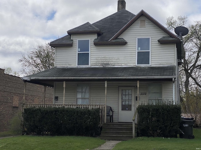 view of front facade featuring a chimney, a porch, a front yard, and roof with shingles