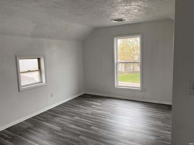 bonus room with dark wood-style floors, visible vents, baseboards, a textured ceiling, and lofted ceiling