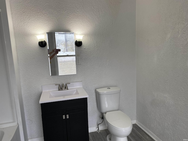 bathroom featuring toilet, wood finished floors, vanity, and baseboards