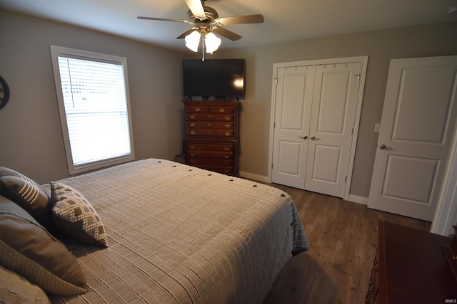 bedroom with baseboards, dark wood-style floors, a ceiling fan, and a closet