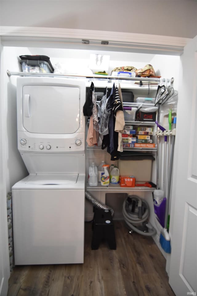 washroom featuring stacked washer / dryer, wood finished floors, and laundry area