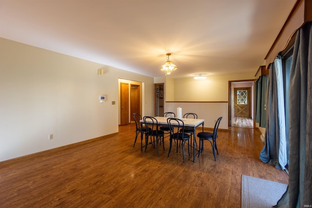 dining area featuring a chandelier, baseboards, and wood finished floors
