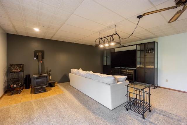 living room with a ceiling fan, carpet flooring, a wood stove, and baseboards