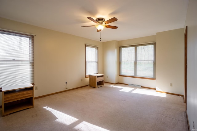 empty room with a ceiling fan, light carpet, and baseboards