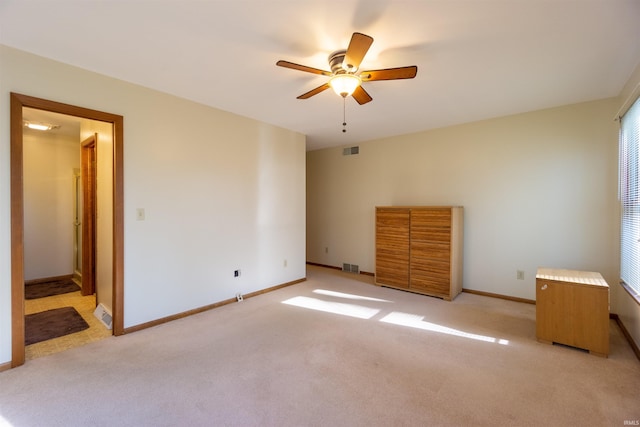 unfurnished bedroom featuring a ceiling fan, visible vents, light carpet, and baseboards