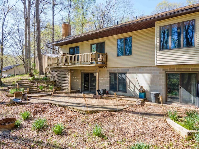 rear view of house featuring a chimney, stairs, a patio, and a wooden deck