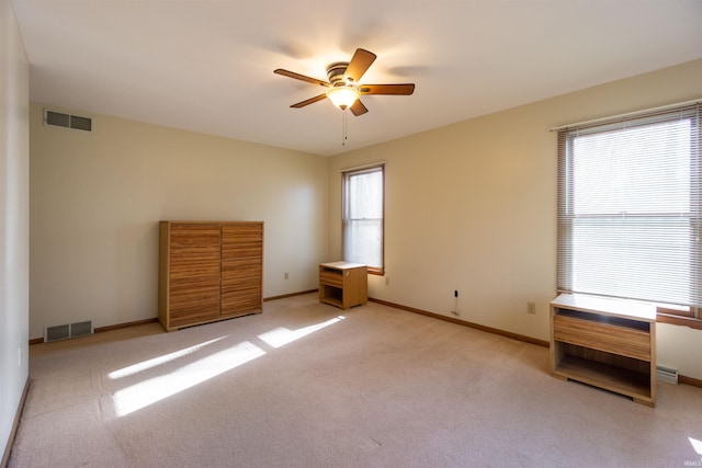 unfurnished bedroom featuring baseboards, visible vents, a ceiling fan, and light carpet