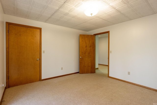 empty room featuring baseboards and light colored carpet