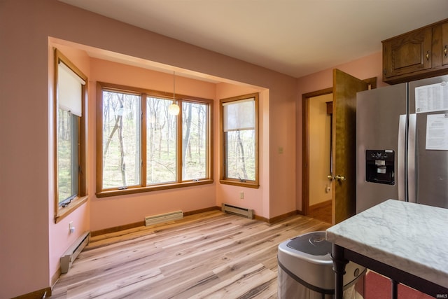 kitchen with stainless steel refrigerator with ice dispenser, baseboard heating, a wealth of natural light, and light wood-style floors
