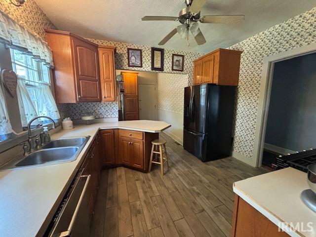 kitchen featuring a sink, wallpapered walls, freestanding refrigerator, and ceiling fan