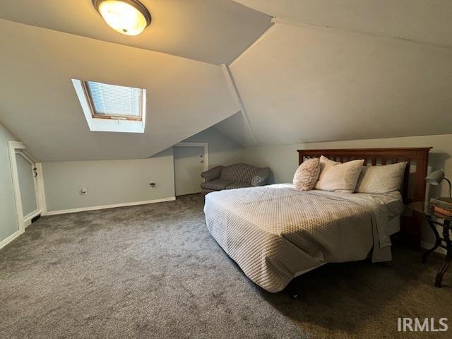 carpeted bedroom featuring baseboards and vaulted ceiling with skylight