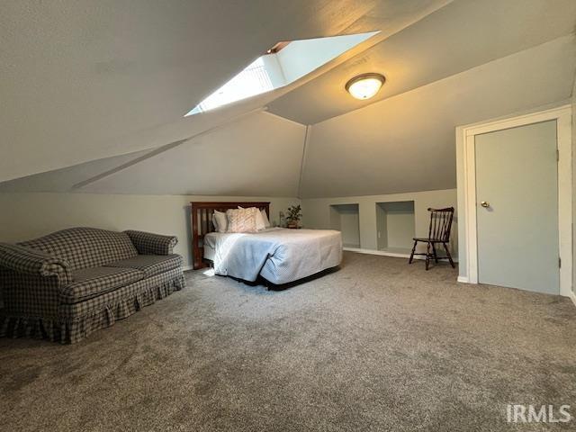 bedroom with lofted ceiling with skylight and carpet flooring