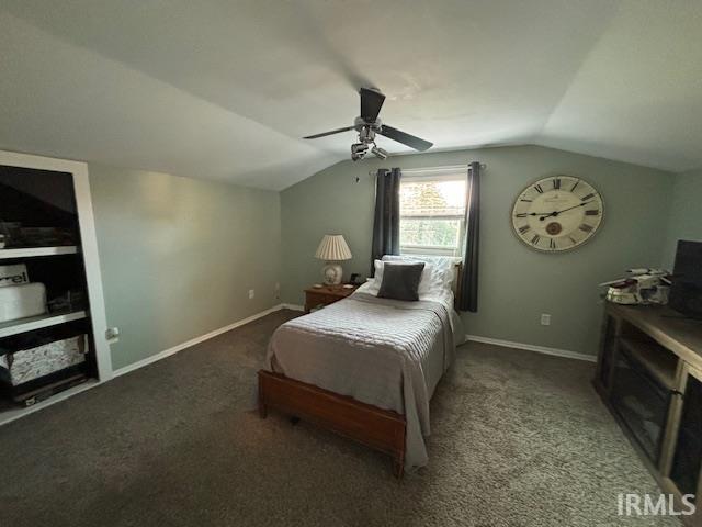 carpeted bedroom featuring a ceiling fan, vaulted ceiling, and baseboards