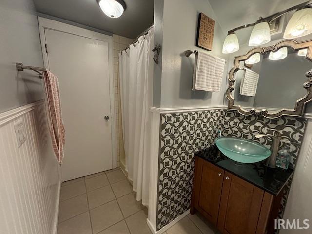 full bathroom featuring a shower with curtain, vanity, wainscoting, and tile patterned floors