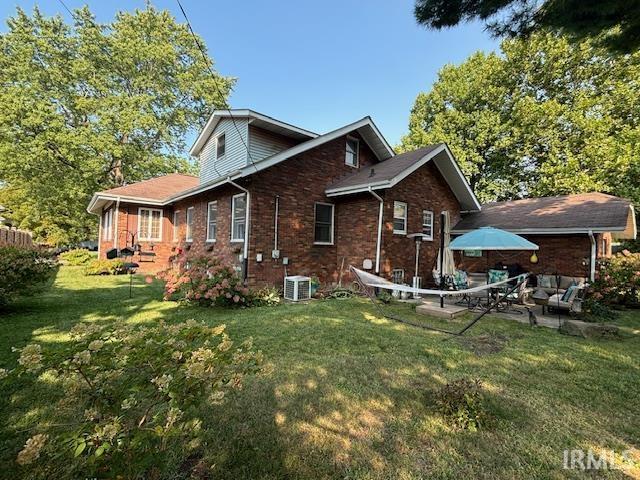 view of home's exterior with brick siding, a patio area, central AC unit, and a lawn