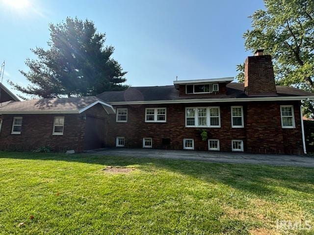 rear view of property with a chimney, a yard, a patio area, and an attached garage