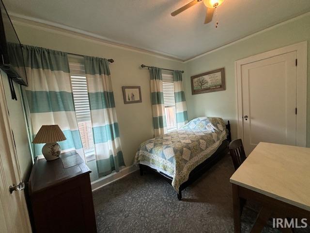 bedroom featuring crown molding, ceiling fan, and dark colored carpet