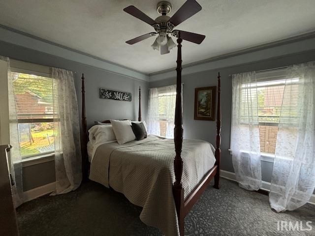 bedroom with baseboards, ornamental molding, a ceiling fan, and carpet flooring