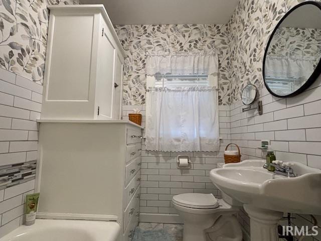 full bath with toilet, a bathtub, wallpapered walls, and tile walls