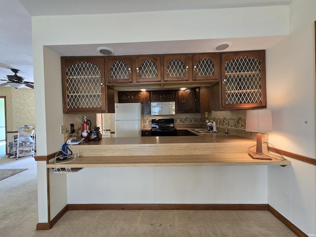 kitchen with white appliances, dark brown cabinets, a peninsula, and a sink